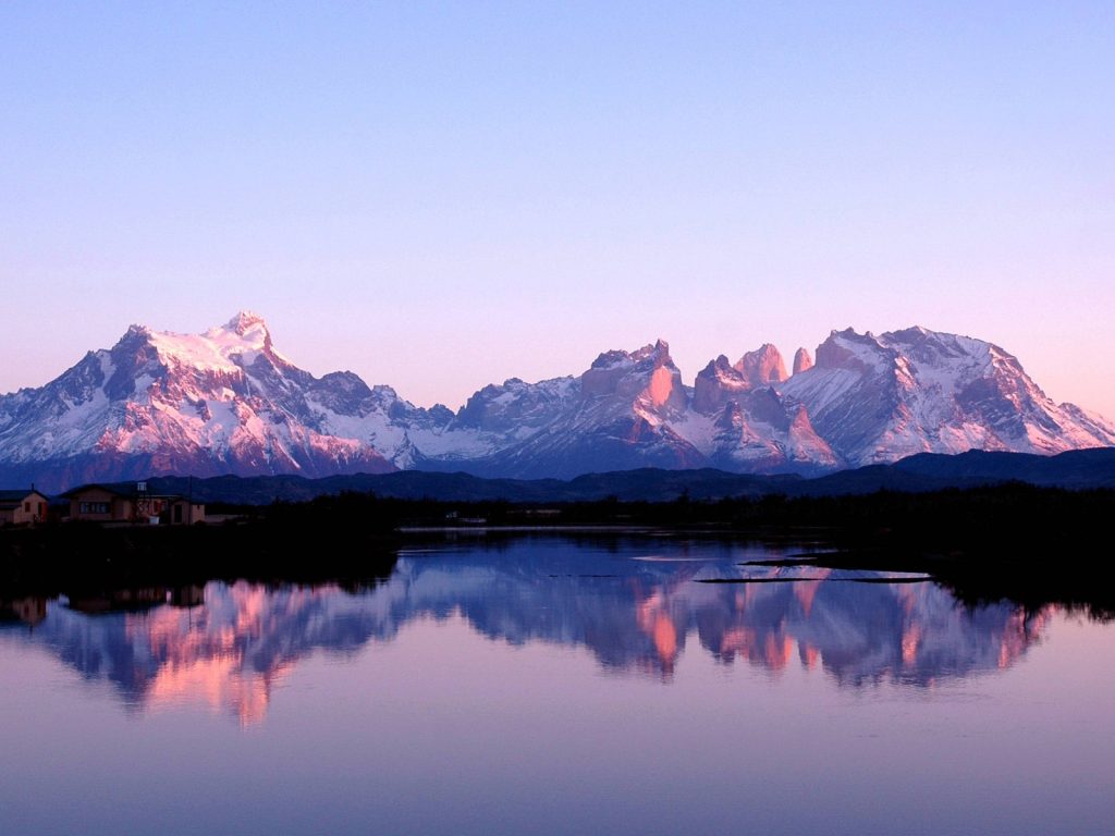 Macizo montañoso de cumbres rocosas y afiladas con presencia de nieve o glaciares. En el entorno se observa vegetación silvestre patagónica y cuerpos de agua (lagos o lagunas). Paisaje natural de clima frío y escala monumental.