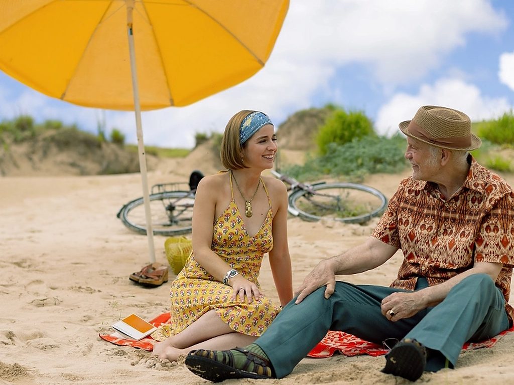 Mariana Di Girolamo y John Malkovich conversando sentados en la playa durante una escena de Wild Horse Nine.