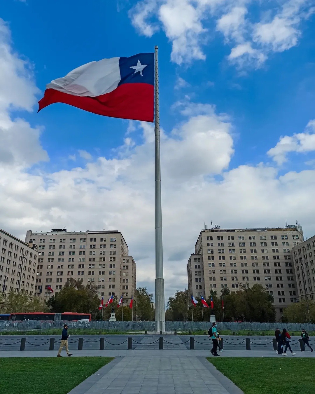 Giant Bicentennial Flag waving on a flagpole in Santiago's Civic District, with buildings in the background.