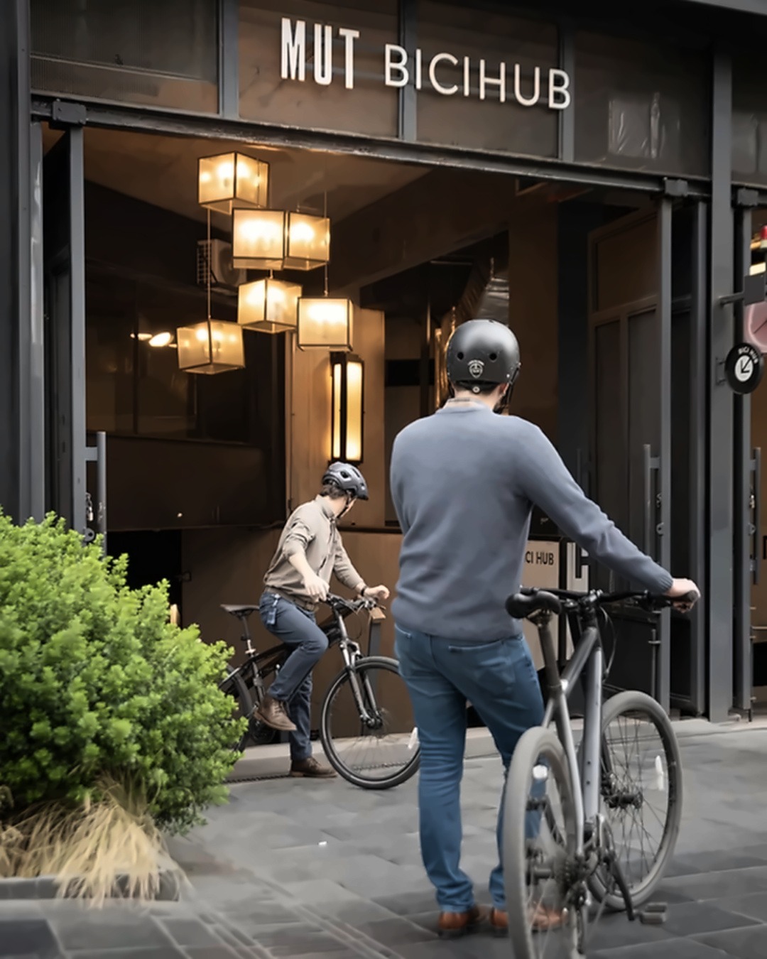 Ciclistas com capacete a entrar no MUT Bicihub, o estacionamento de bicicletas do Mercado Urbano Tobalaba em Santiago.