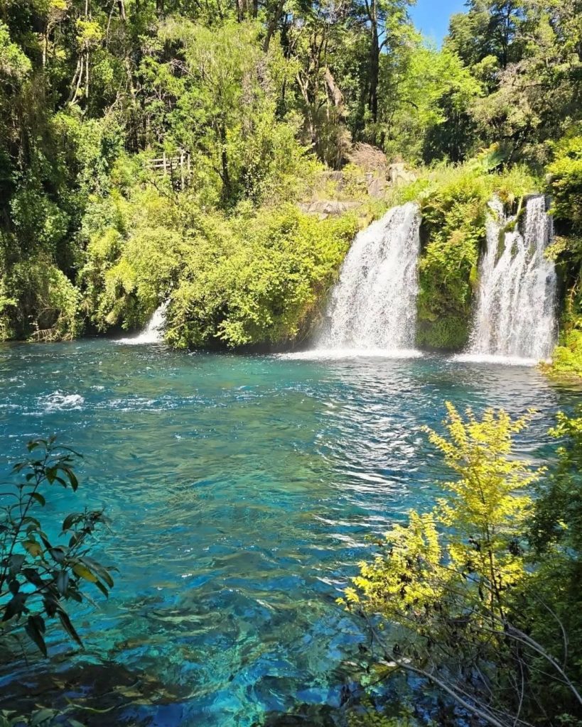 Cascadas que caen sobre una laguna de aguas turquesa rodeada de bosque en los Ojos del Caburgua, cerca de Pucón.