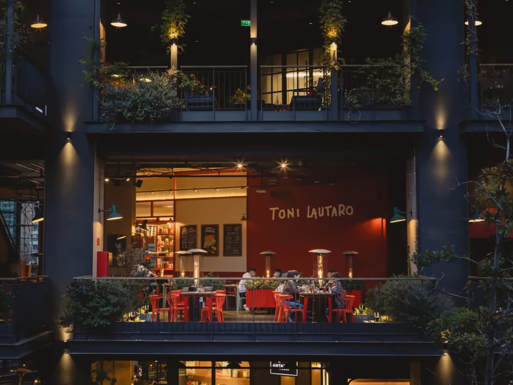 Terraza de Toni Lautaro con sillas rojas y estufas encendidas de noche en el cuarto piso del MUT, una pizzería napolitana.